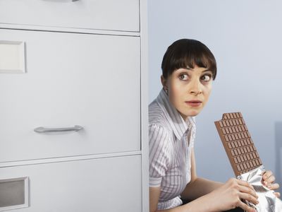 办公室工作者隐藏和吃一块大块巧克力