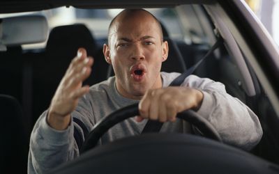 在另一个司机的一个愤怒的人姿态，而在车轮后面