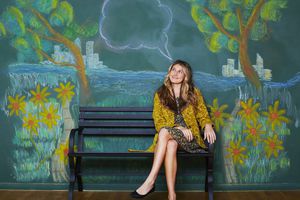 一个女人坐在长凳上，前面是一幅粉笔壁画