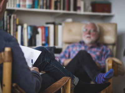 一个男人，坐在椅子上，和他的心理医生交谈
