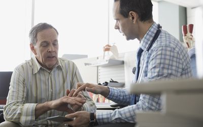 A senior working with a doctor in an office.