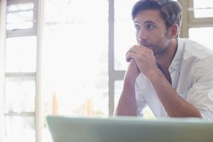 男子坐在笔记本电脑“class=