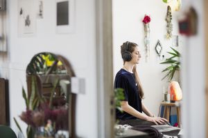 思考在她的有耳机的公寓的妇女