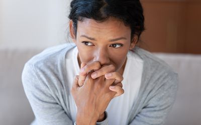 一个焦虑，可怕的年轻女子在她的脸上扣掉她的手