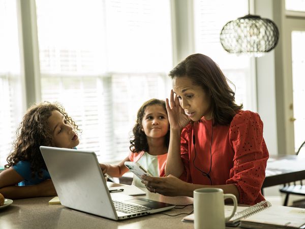 Stressed out woman trying to work and deal with children.