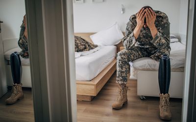 老兵双手抱着头坐在床边