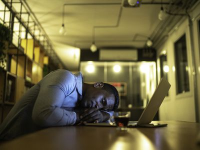 一个男人在笔记本电脑前的桌子旁睡着了