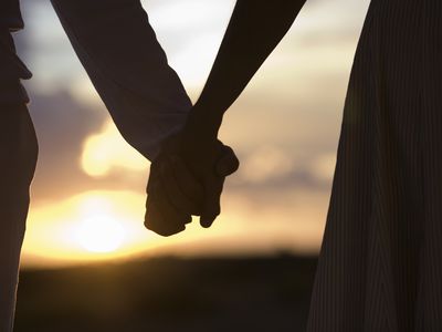 成熟的夫妇在日落时牵着手，特写