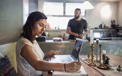 侧面的女人在餐桌,而人站在工作背景