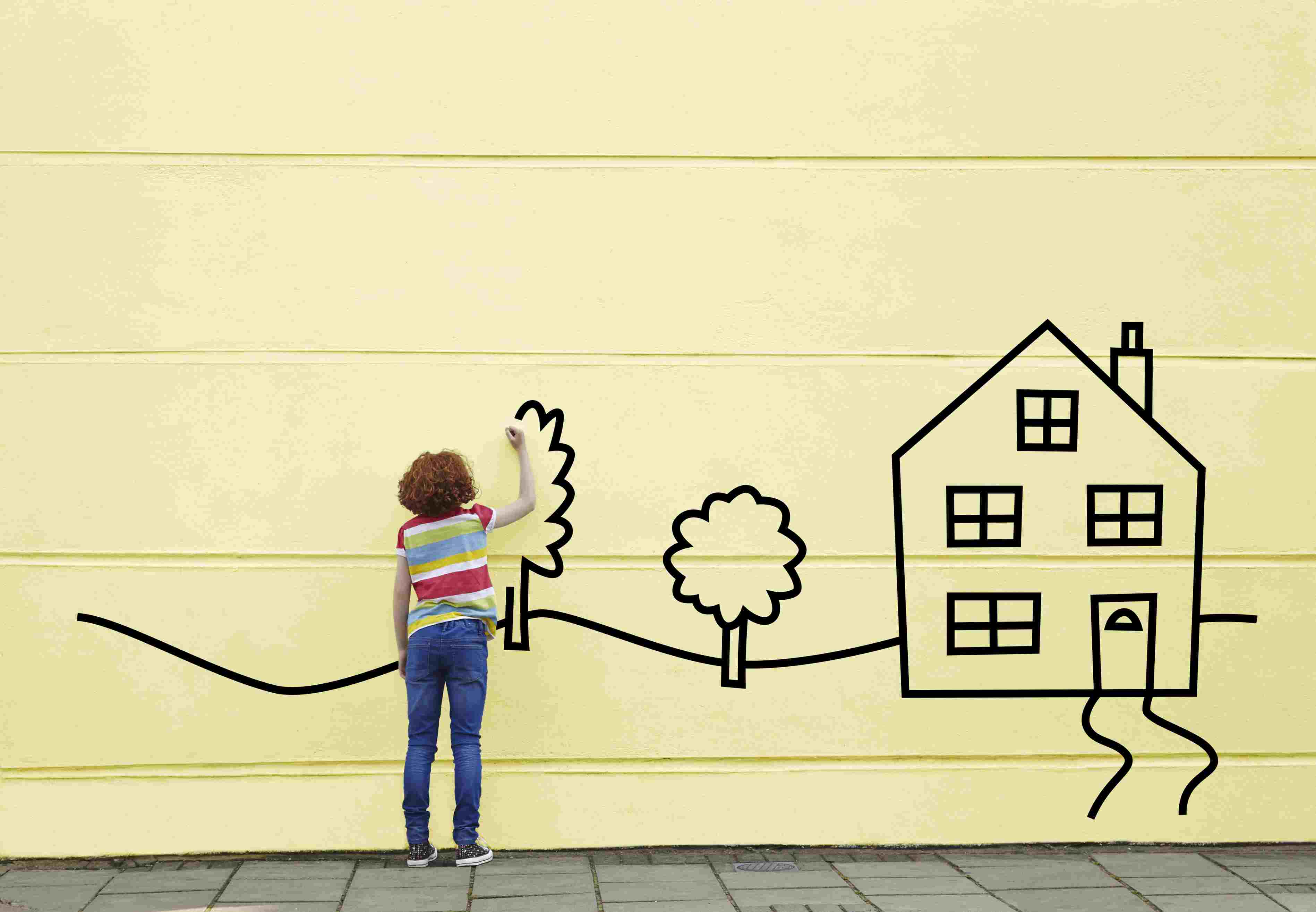 女孩在墙上画房子和树