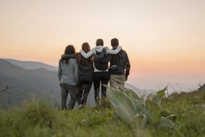 group of hikers standing on viewpoint at sunset