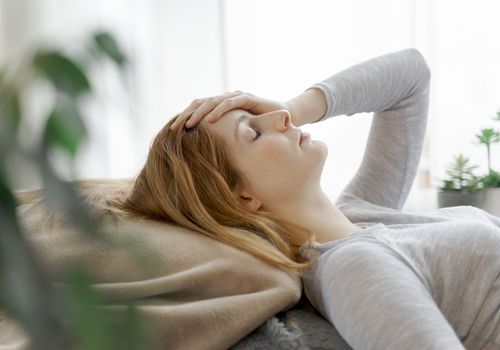 一名妇女在枕头上躺在枕头上，她的眼睛闭着眼睛和手在她的头上。