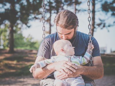 在秋千上抱着婴儿的男人