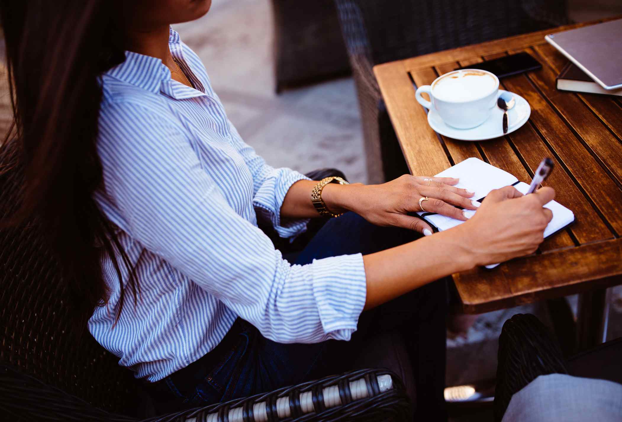 做在坐在城市咖啡馆的日志的年轻女实业家笔记