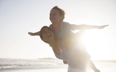 Woman carying boy on beach