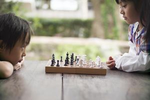 两个亚洲小孩在外面的桌子上下棋