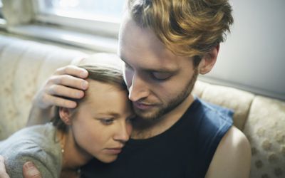 年轻男子在沙发上拥抱严肃的女子