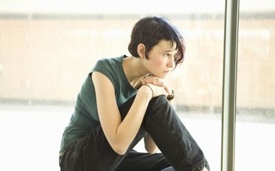 悲伤的少女独自一人坐在前面的窗口