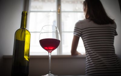 看与杯的妇女窗口在桌上的酒