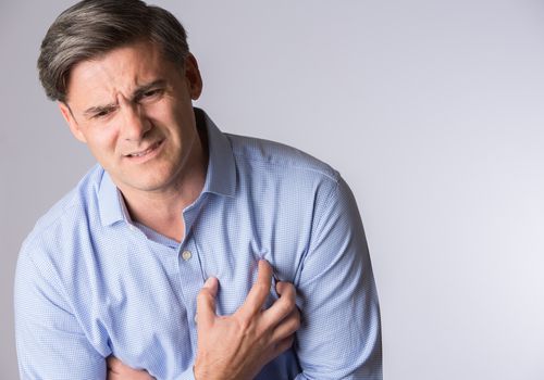 anxious appearing man holding his chest in pain