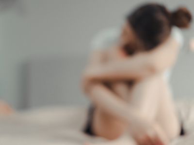 blurry photo of a sad woman sitting on her bed