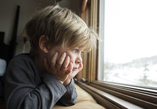 Sad looking boy looking out a window