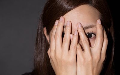 害怕的妇女通过她的手偷看