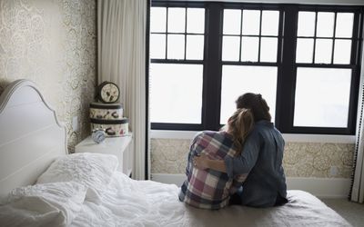 母亲抱着坐在床上的女儿