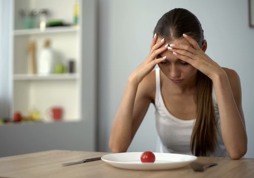 一个女人看着盘子里的一小部分食物。