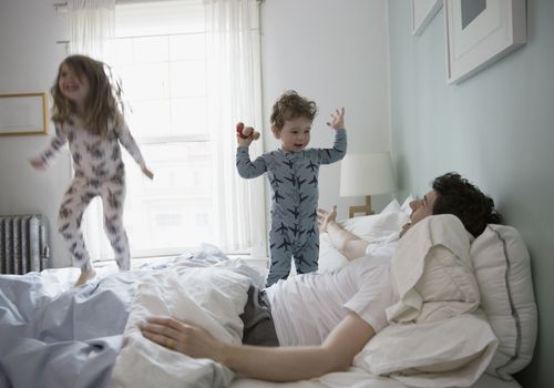 dad with kids jumping on bed