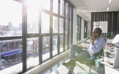 沉思的商人在阳光明媚的办公室窗口