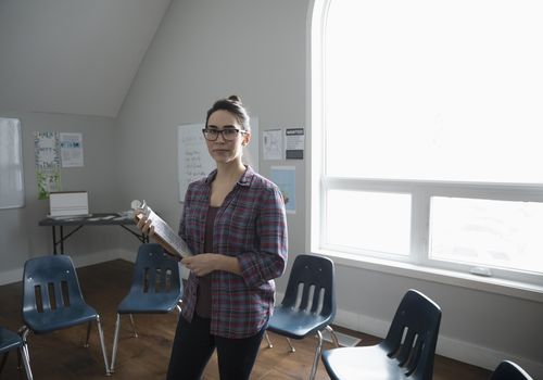 Woman with clipboard standing in the middle of a circle of chairs