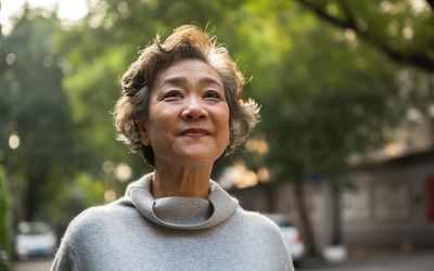 开朗的资深妇女放松画象室外，站立在路在城市