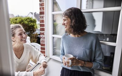 两个愉快的妇女通过窗口谈话