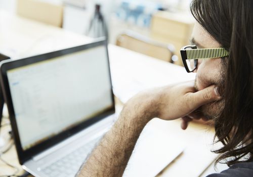 man using a laptop with his hand on his chin