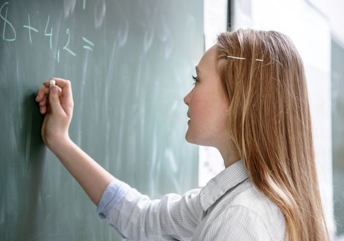 A schoolgirl doing mathematics at chalkboard