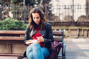Young woman writing in notebook outside