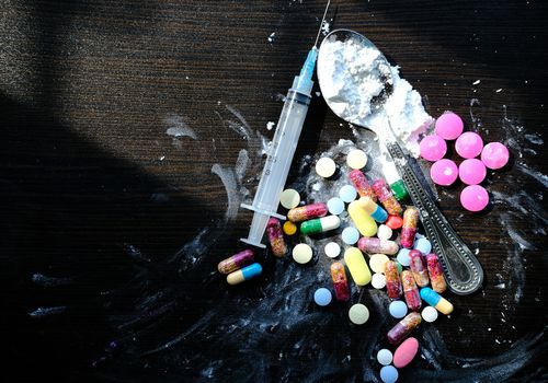 药片，注射器和勺子放在木桌上