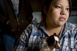 sad girl holding a chihuahua looking out of window