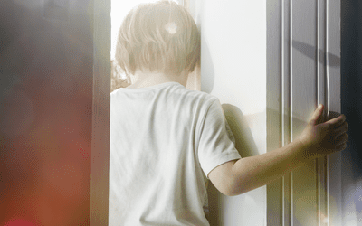 悲伤的孩子抱着门框