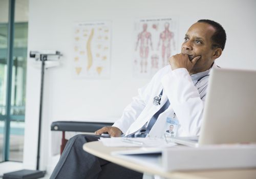 Thoughtful male doctor sitting at desk in hospital