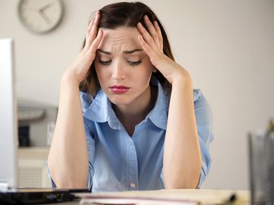 有她的头的被注重的妇女在她的手上在工作台