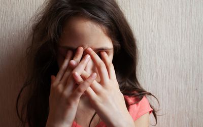 长头发的小女孩用手照遮住了脸