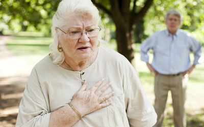 senior woman with shortness of breath and chest pain, senior man in background