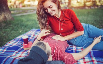 一对年轻的女同性恋夫妇在公园里一起躺在毯子上。