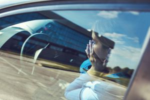 坐在汽车的困厄的妇女用在她的面孔的手