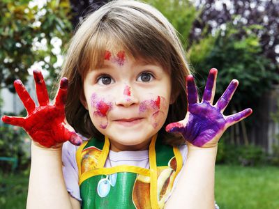 有油漆的女孩遍布她的面孔和手