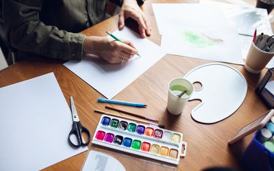 关闭与油漆和铅笔的人图画在家。远程教育，创意职业，艺术疗法