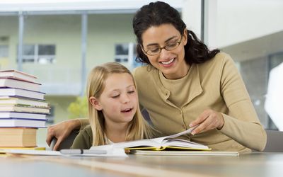 woman helping child read book