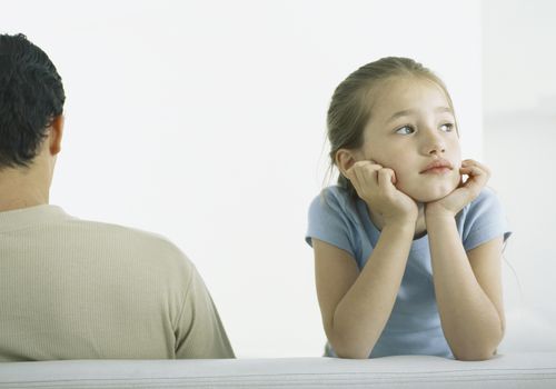 Girl holding head, leaning on elbows next to man, rear view